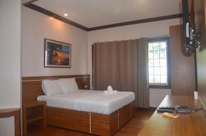 a bedroom with a bed and a desk and a window at Robinland Vacation Home in Badian