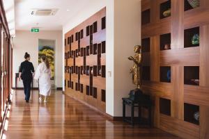 um casal a andar por um corredor com uma parede de garrafas de vinho em Cable Beach Club Resort & Spa em Broome