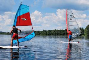 two people on surfboards with sails on the water at Sventes Rasa in Kaķīši