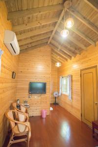Habitación con paredes de madera, TV y sillas. en 翠谷山莊Cui Gu Villiage, en Lugu