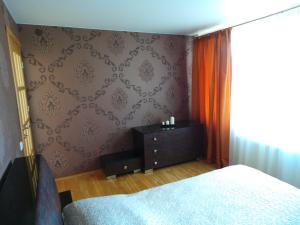 ein Schlafzimmer mit einem Bett und einer Kommode neben einem Fenster in der Unterkunft Cozy apartment with a wonderful lake view in Telšiai