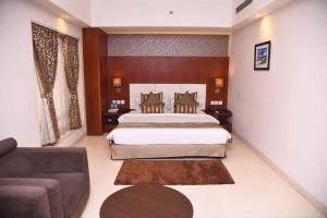 a bedroom with a large bed and a couch at Celesta Hotel - Kolkata in Kolkata