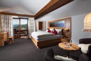 ein Hotelzimmer mit einem Bett und einem Wohnzimmer in der Unterkunft Alpenhotel Denninglehen in Berchtesgaden