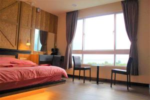 1 dormitorio con cama, escritorio y ventana en 巴斯拉岸民宿 en Chenggong