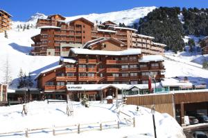 un grand hôtel dans la neige avec des bâtiments recouverts de neige dans l'établissement CMD Méribel, à Méribel