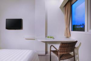 a bedroom with a bed and a table and a window at favehotel Simpang Lima - Semarang in Semarang