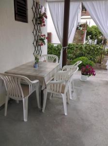 einen Holztisch und vier weiße Stühle auf einer Terrasse in der Unterkunft Nada Apartment in Bilice