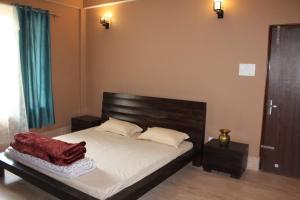 a bedroom with a bed with a wooden headboard at Denzong House in Kalimpong