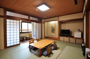 Habitación grande con mesa de madera y sillas. en Obokekyo Mannaka, en Miyoshi