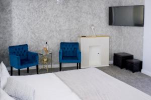 ブカレストにあるBrater Luxuryのベッドルーム1室(ベッド1台、青い椅子2脚、テレビ付)