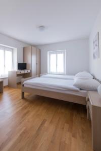 a large bed in a white room with wooden floors at Hôtel-de-Ville d'Attalens in Attalens