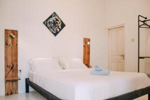 um quarto com uma grande cama branca com uma fotografia na parede em Pojok Pas em Yogyakarta