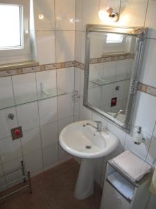 a white bathroom with a sink and a mirror at Apartments Nives in Supetar