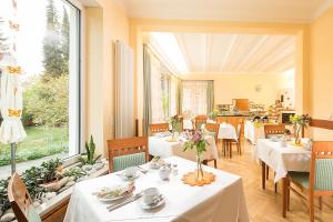 restauracja z białymi stołami i krzesłami oraz dużym oknem w obiekcie Villa Arborea w Augsburgu