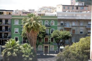 un edificio verde con una palmera delante en La Libra Rooms, en Cagliari