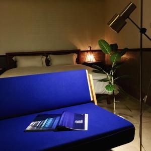 um quarto com uma cama azul com um livro em OrigInn Space em Taipei