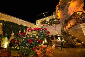 un patio con rosas rojas, mesa y sillas en Roma Cave Suite, en Göreme