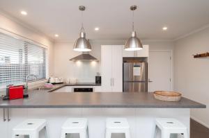 a kitchen with a counter with stools in it at Luxury Rata Apartment - A in Twizel