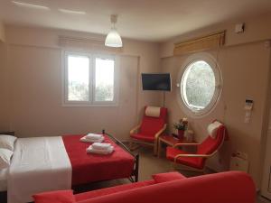 a bedroom with a bed and two chairs and a tv at La Sirenetta Residence in Sivota