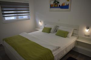 a bedroom with a large white bed with green pillows at Bozikovic 365 in Podstrana