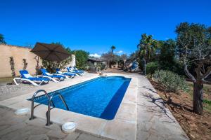 a swimming pool with chairs and an umbrella at Can Cusina in Es Llombards