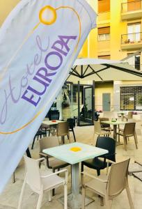 un restaurant avec des tables, des chaises et un drapeau dans l'établissement Hotel Europa, à Arma di Taggia