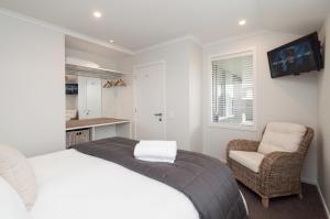 um pequeno quarto com uma cama e uma cadeira em Luxury Rata Apartment - B em Twizel