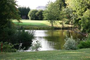 a pond in the middle of a golf course at Manor Of Groves Hotel, Golf & Health Club in Sawbridgeworth