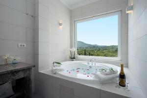 a white bathroom with a tub with a window at Gem Villa in Viros Corfu in Virós +21 photos