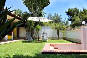 a yard with two chairs and an umbrella at Villetta Carla in Fontane Bianche