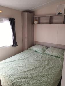 een slaapkamer met een bed met een groen dekbed en een raam bij Chalet Dalile IJmuiden aan Zee vlakbij het strand in IJmuiden
