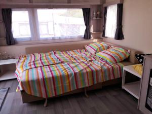 a bedroom with a bed with a colorful comforter at Chalet Dalile IJmuiden aan Zee vlakbij het strand in IJmuiden