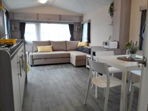 Il dispose d'une cuisine et d'un salon avec un canapé et une table. dans l'établissement Chalet Dalile IJmuiden aan Zee vlakbij het strand, à IJmuiden