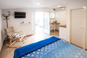 a bedroom with a bed and a chair and a kitchen at Apartments Aria in Zadar