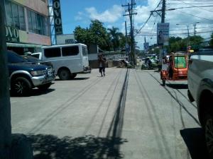 una persona che cammina per una strada cittadina con veicoli di Asia Novo Boutique Hotel - Roxas a Roxas City