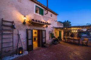a house with a patio and a table in front of it at Can Cusina in Es Llombards