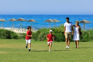 a family walking on the grass near the beach at Verdura Resort in Ribera