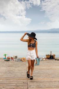 Una donna che cammina su un molo con un cappello di Sato Design Hotel a Çeşme