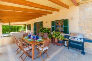 a patio with a wooden table and a stove at Cas Garriguer in Andratx