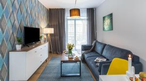 a living room with a couch and a tv at Vistula Boutique Exclusive Apartments in Krakow