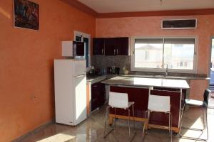cocina con nevera blanca y algunas sillas en Villa De Plage, en Riah