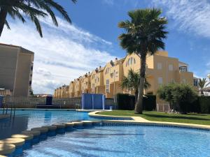 una piscina con palmeras y edificios en Sueños de Denia I -Serviden, en Denia