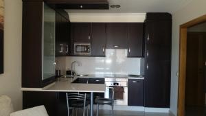una cocina con armarios de color marrón oscuro y fregadero en Apartamento La Cantera, en Combarro