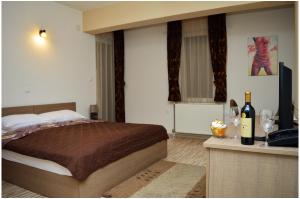 - une chambre avec un lit, une télévision et des bouteilles de vin dans l'établissement Hotel Treff, à Bitola
