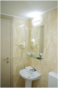 La salle de bains est pourvue d'un lavabo et d'un miroir. dans l'établissement Hotel Treff, à Bitola