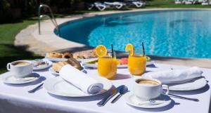 托雷莫利諾斯的住宿－MS特羅皮卡納酒店，一张桌子,旁边是游泳池,摆放着食物和饮料