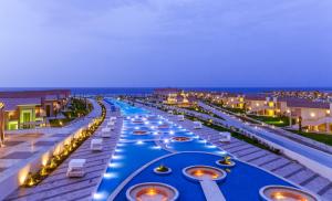 a hotel pool with boats in it at night at Pickalbatros Sea World Resort - Marsa Alam- "Aqua Park" in Quseir