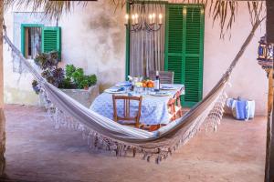 a hammock hanging on a patio with a table and chairs at Can Cusina in Es Llombards