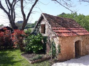 an old stone building in a yard with flowers at Les Gîtes de l'Orta in Saint-Jean-dʼEyraud