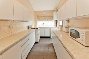 a large kitchen with white cabinets and a microwave at Sweet Dreams Residence, close to Penny Lane in Liverpool